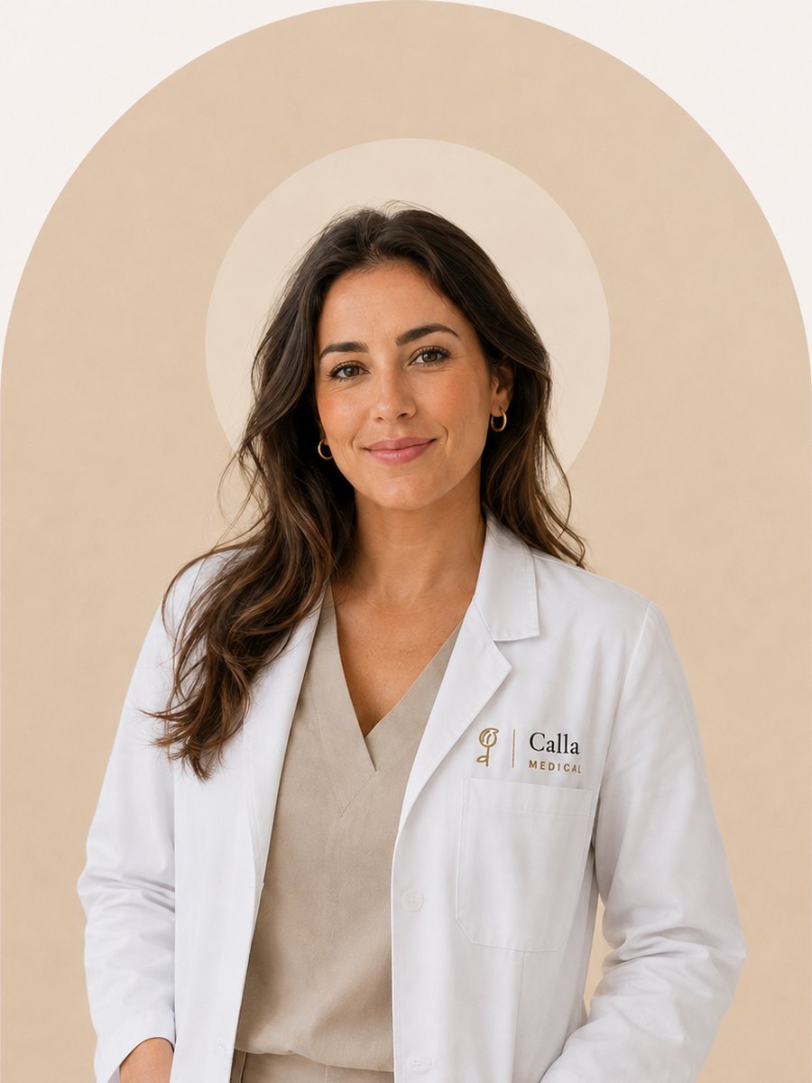 Yasmin El Amrani, zorgcoördinator bij Calla Medical, in witte jas tegen een crèmekleurige boog